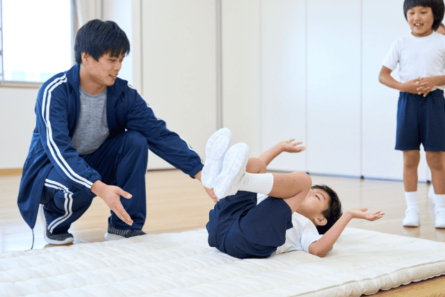 前転をする男の子と補助をする男性