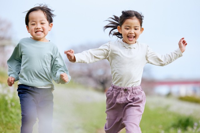 河辺を笑顔で走るふたりの子ども