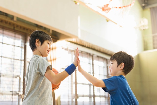 バスケットコートでハイタッチしている男の子2人