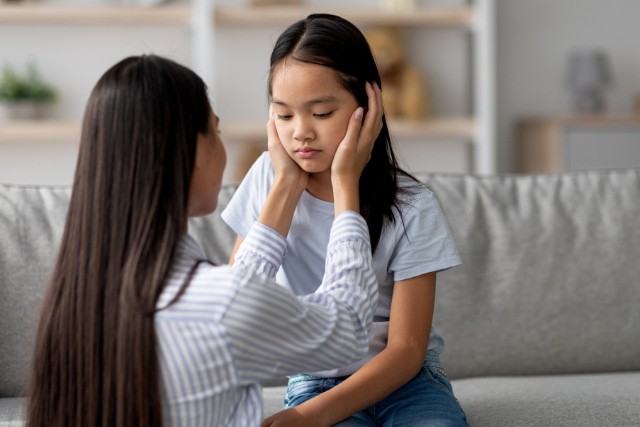 子供の頬に手を当てる母親