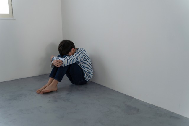 部屋の隅でうずくまる男の子