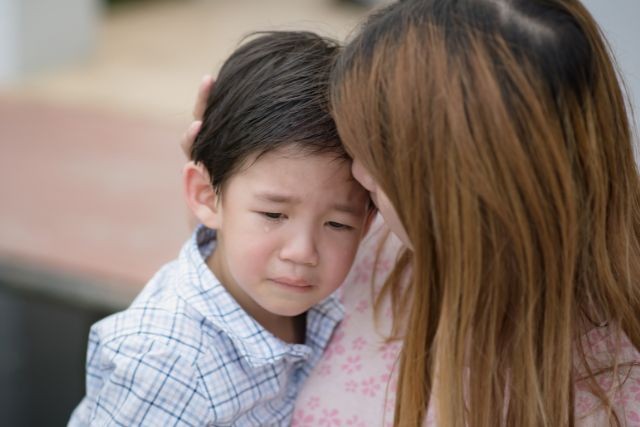泣きそうな男の子を慰めている母親