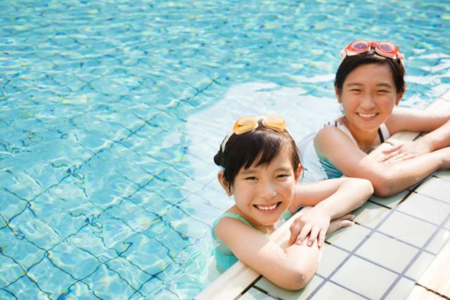 プールのふちにいる小学生