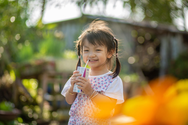 ジュースの紙パックをストロー飲んでいる女の子