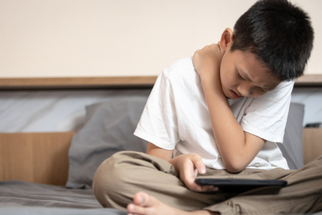 猫背でゲームをしているこども