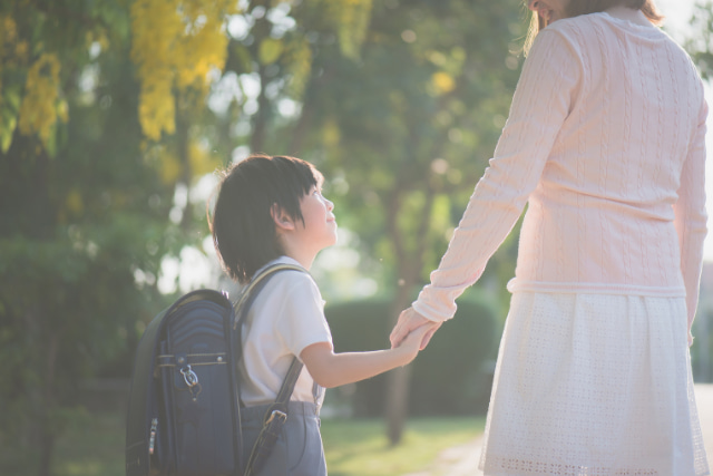 小学生と手をつないでるお母さん