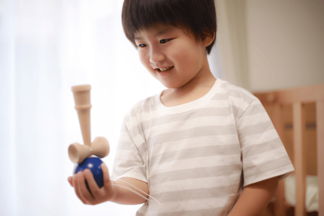 球を手に持ってけん玉で遊ぶ子ども
